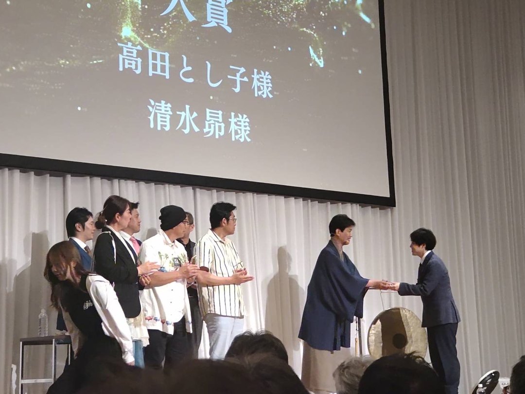 AIの学校「飛翔」2周年イベントの表彰式で、代表の清水昴が賞状を受け取っている場面