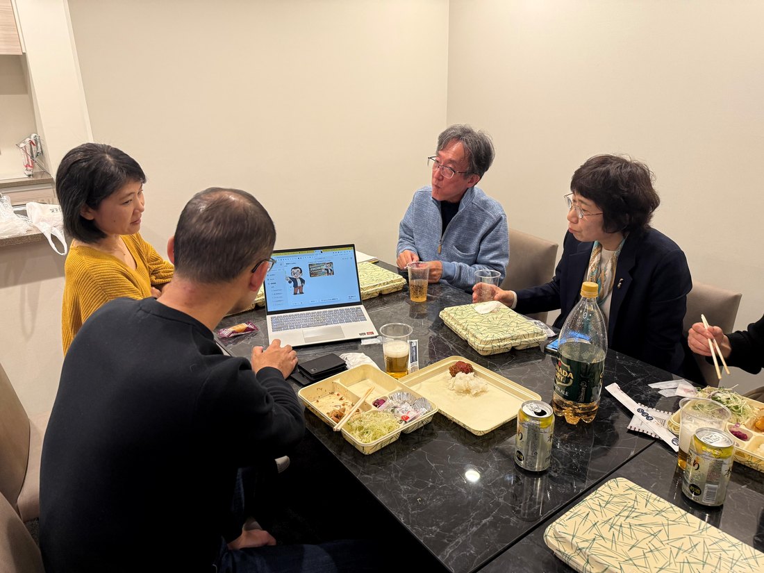 AI×出版コミュニティの懇親会で、参加者がノートパソコンの画面を囲みながら話している様子